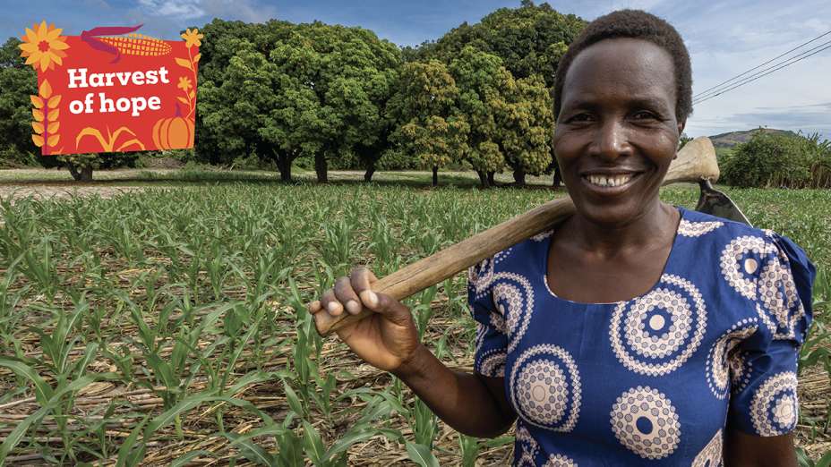 Nyarai stands smiling at the camera in her maize farm.