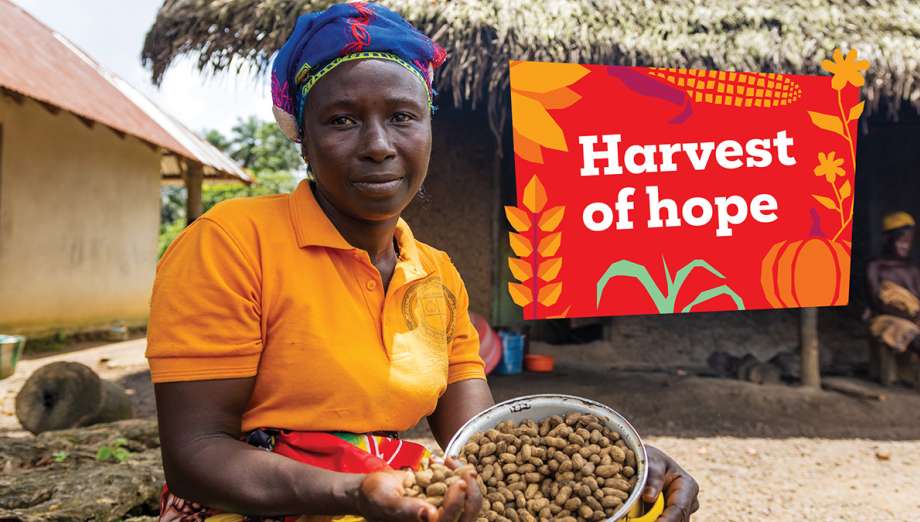 The same woman holds a bowl of harvested groundnuts outside her home, beside the "Harvest of hope" sign.