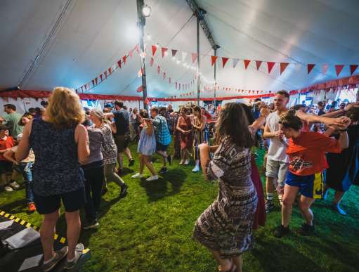 People dancing at dancing in a large tent at a festival