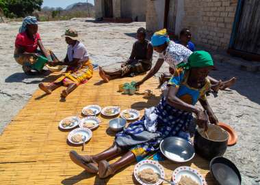 Janet Zirugo is dishing a delicious traditional rice with home made peanut. She has just cooked this meal and is proud to dish for her family. In the background is Nyarai and Chipo, her daughters as well as her 2 daughters in-law- Esnath and Nomatter.