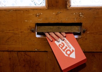 Christian Aid envelope being posted through the letterbox.